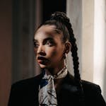 Portrait of an elegant woman in stylish attire with braided hair, showcasing modern fashion.